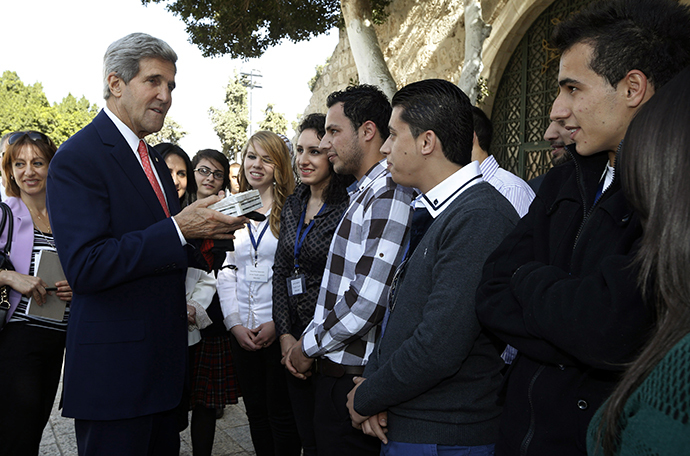 US Secretary of State John Kerry is offered a gift by young Palestinian people during a visit near Manger Square on November 6, 2013 in the West Bank city of Bethlehem. (AFP Photo / Jason Reed)