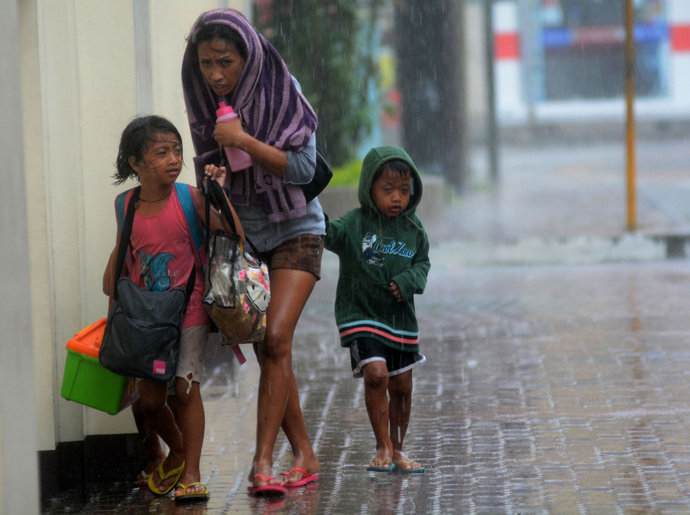 A mother and her children brave heavy rains as they head for an evacuation center amidst strong winds as Typhoon Haiyan pounded Cebu City, in central Philippines on November 8, 2013 (AFP Photo)