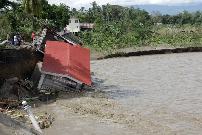 People look at a damaged village hall in the aftermath of Super Typhoon Haiyan in Iloilo on November 9, 2013. (AFP Photo / Tara Yap)