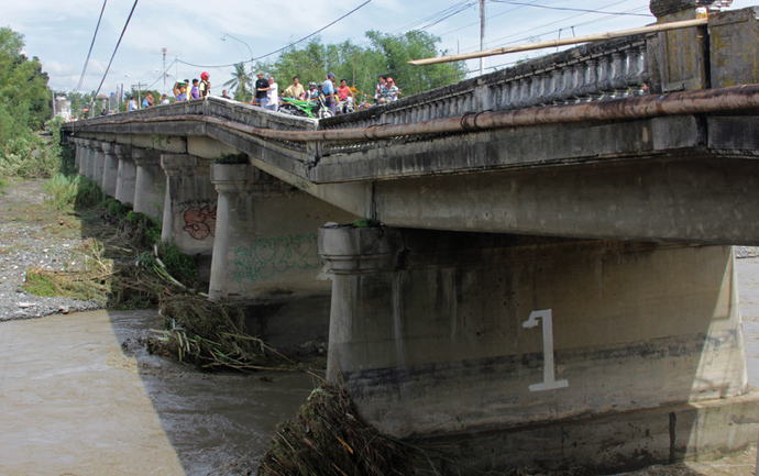 People look at a damaged bridge in the aftermath of Super Typhoon Haiyan in Iloilo on November 9, 2013. (AFP Photo / Tara Yap)