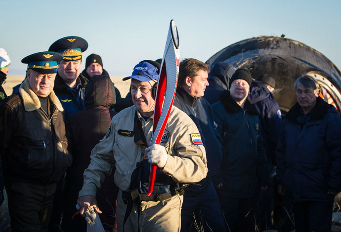 A member of ground personnel carries the torch of the 2014 Sochi Winter Olympic Games delivered from orbit in the Soyuz TMA-09M capsule after its landing in a remote area near the town of Zhezkazgan in central Kazakhstan November 11, 2013. (Reuters / Shamil Zhumatov)