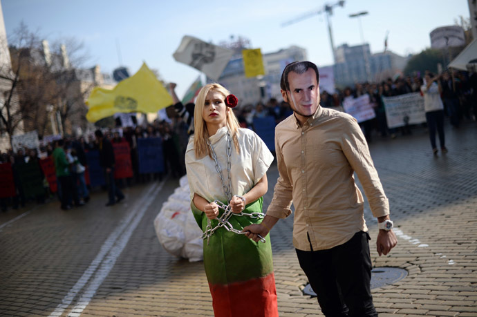 A student with a mask of Bulgarian Prime minister Plamen Oresharski pulls another chained student, wraped with Bulgarian national flag during an anti-government protest in Sofia on November 10, 2013. (AFP Photo/Dmitar Dilkoff)