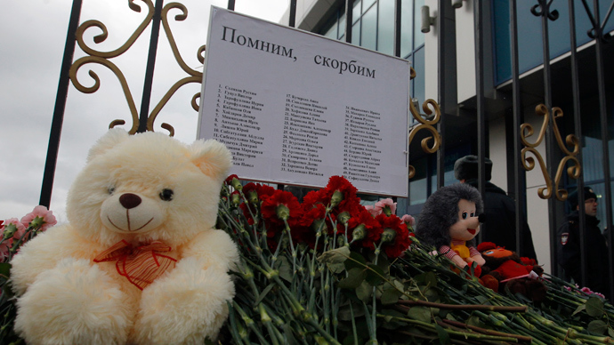 Flowers and stuffed toys, part of a makeshift memorial, are seen left near a fence of Kazan airport, under a sign giving the names of the victims of a Tatarstan Airlines Boeing 737 crash, November 18, 2013 (Reuters / Maxim Shemetov)