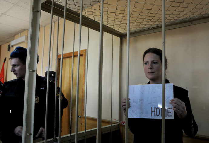 Greenpeace International activist, one of the "Arctic 30," Ana Paula Alminhana Maciel from Brazil, holds a poster as she stands in a defendant cage in a court in Russia's second city of Saint Petersburg, on November 18, 2013.(AFP Photo / Olga Maltseva)