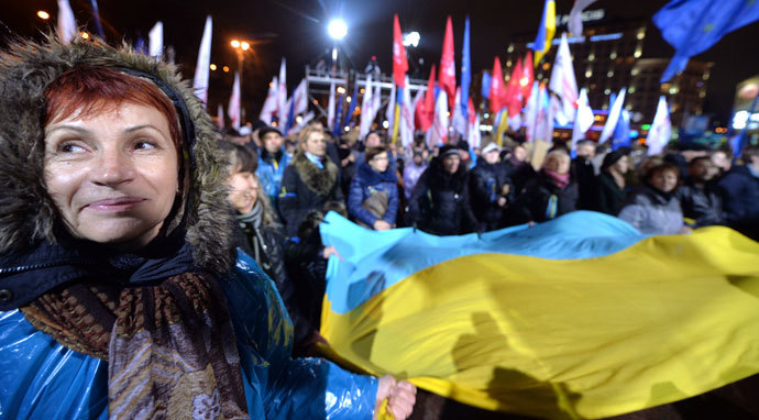 A woman together with other protesters waves an Ukrainian national flag during a rally of the opposition on European Square, on a second day of protests over the government's decision to scrap a key pact with the EU, in Kiev on November 25, 2013.(AFP Photo / Sergei Supinsky)
