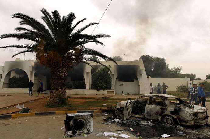 Libyan men stand outside a building used by Ansar al-Sharia militia after it was torched by residents on November 25, 2013 in Benghazi. (AFP Photo / Abdullah Doma)