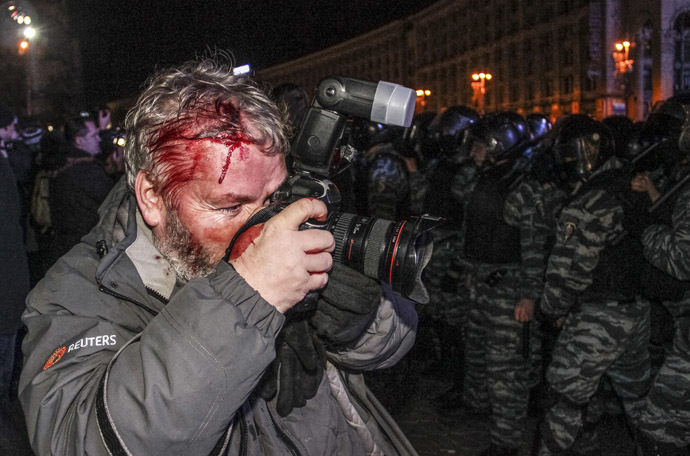 Wounded Reuters photographer Gleb Garanich, who was injured by riot police, takes pictures as riot police block protesters during a scuffle at a demonstration in support of EU integration at Independence Square in Kiev November 30, 2013. (Reuters)