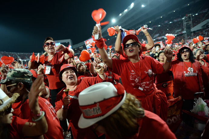 Thai pro-government Red Shirt supporters wave clappers and cheer leaders' speeches during a rally at a stadium in Bangkok on November 30, 2013. (AFP Photo/Christophe Archambault)