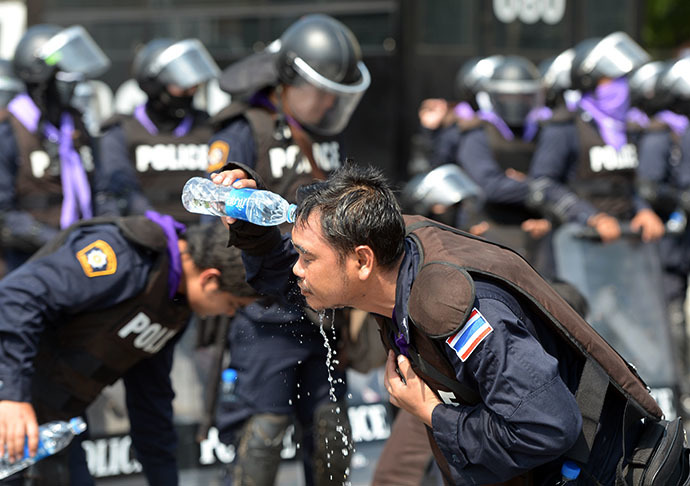 Thai riot policemen clean their faces from tear gas during an anti-government demonstration at Government House in Bangkok on December 1, 2013. (AFP Photo / Pornchai Kittiwongsakul)