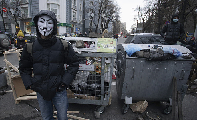 A protester wearing a Guy Fawkes mask stands in front of a barricade near the government building in Kiev December 2, 2013. (Reuters / Stoyan Nenov)