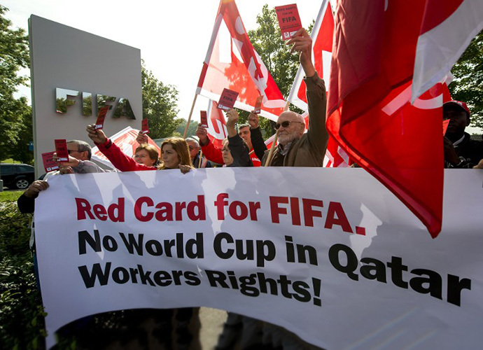 Members of Building and Wood Workers' International (BWI) and Swiss Unia unions hold a red cards reading "A red card for FIFA, no World Cup without labour rights" and a banner reading "No World Cup in Qatar Workers Rights!" during a demonstration outside the headquarters of the world's football governing body FIFA in Zurich on October 3, 2013. (AFP Photo / Fabrice Coffrini)