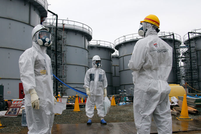 Tokyo Electric Power Corp's (TEPCO) official (C) and journalists wearing protective suits and masks stand in front of storage tanks for radioactive water in the H4 area, where radioactive water leaked from a storage tank in August, at the tsunami-crippled TEPCO Fukushima Daiichi nuclear power plant in Fukushima prefecture November 7, 2013.(Reuters / Kimimasa Mayama)