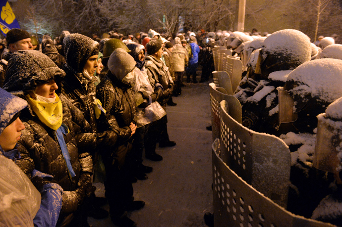 Pro-EU Ukrainian protesters stand opposite riot policemen securing the area outside the presidential office in Kiev on December 9, 2013 (AFP Photo / Sergey Supinsky)