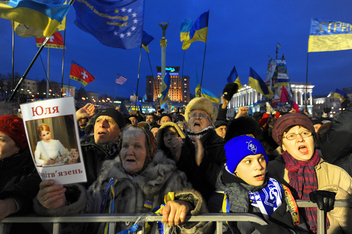 People shout slogans and wave Ukrainian and European Union flags as a woman holds a picture of jailed former Prime Minister Yulia Tymoshenko during a mass rally on Independence Square in Kiev, on December 15, 2013. (AFP Photo / Viktor Drachev)
