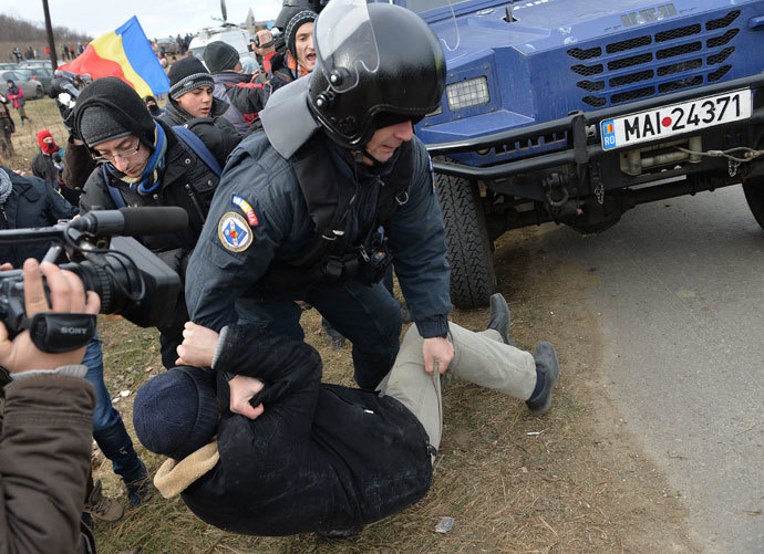 A Romanian protester is lifted by a Romanian gendarme after protesters teared down the fence of the exploring perimeter of US energy giant Chevron in Pungesti, Romania on December 7, 2013. (AFP Photo / Daniel Mihailescu)