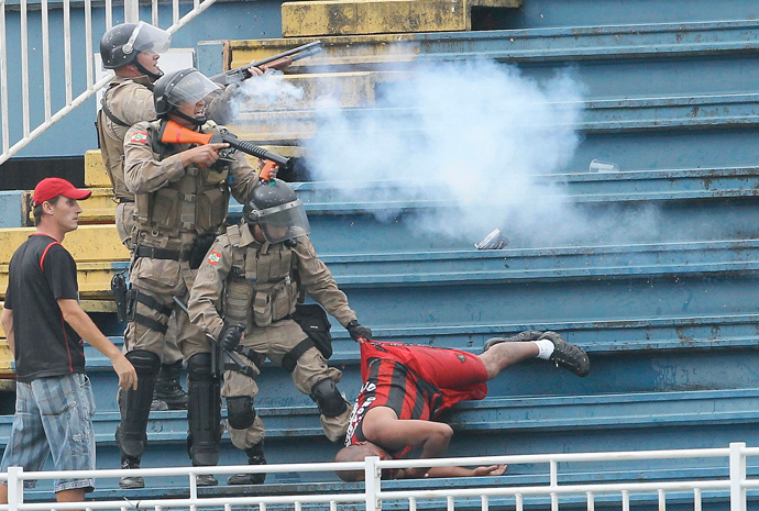 Policemen fire rubber bullets as they help an Atletico Paranaense fan during clashes between Vasco da Gama soccer fans and Atletico Paranaense fans at their Brazilian championship match in Joinville in Santa Catarina state December 8, 2013. (Reuters / Carlos Moraes / Agencia O Dia)
