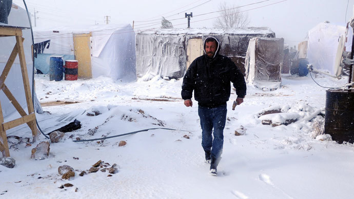 A man walks with a hammer after fixing plastic covers on tents in the snow-covered makeshift refugee camp of Terbol near the Bekaa Valley town of Zahleh in eastern Lebanon on December 11, 2013. (AFP Photo / STR)