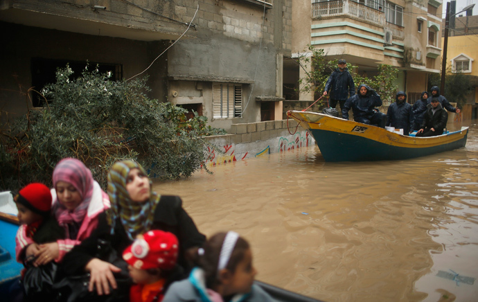 Palestinian policemen loyal to Hamas ride a boat as members of a Palestinian family travel on a boat after being evacuated from their house that is flooded with rainwater on a stormy day in the northern Gaza Strip December 14, 2013. (Reuters / Mohammed Salem) 
