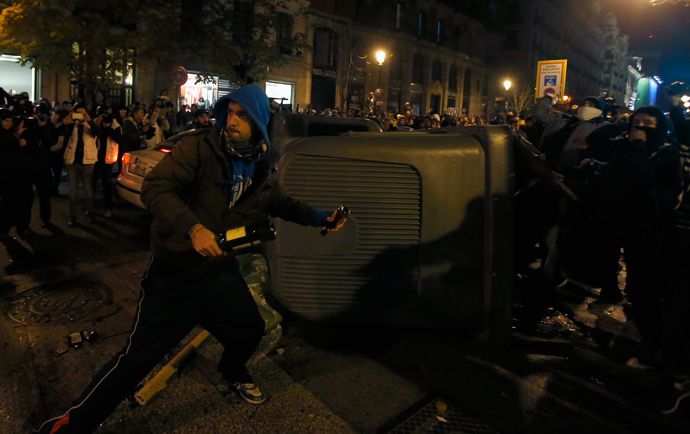 A protester throws a glass bottle during clashes with police at the end of a protest against a new security law in Madrid December 14, 2013. (Reuters / Sergio Perez)