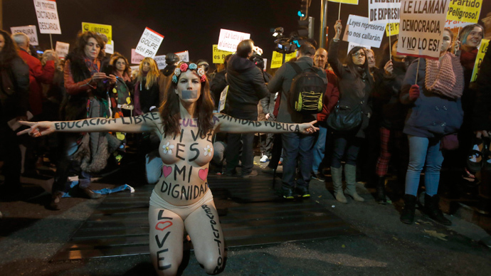 A semi-naked protester kneels near the Parliament building during a protest against a new security law in Madrid December 14, 2013. (Reuters / Sergio Perez)