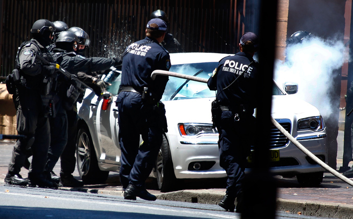 Heavily armed police officers prepare to drag a man from his car outside the New South Wales state parliament building in Sydney December 20, 2013. (Reuters / David Gray)