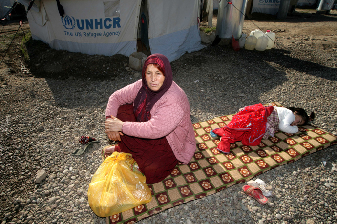 A Syrian-Kurdish refugee woman sits with a child next to a tent provided by the United Nations High Commissioner for Refugees (UNHCR) at the Quru Gusik (Kawergosk) refugee camp, 20 kilometers east of Arbil, the capital of the autonomous Kurdish region of northern Iraq (AFP Photo / Safin Hamed) 