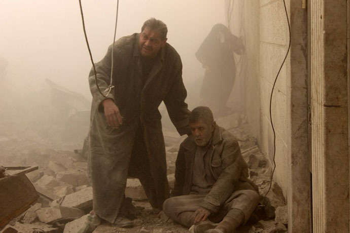 A Syrian man helps an injured man following an airstrike in Aleppo's Maadi neighborhood on December 17, 2013. (AFP Photo / Mohammed Al-Khatieb)