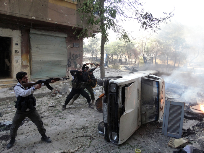 Opposition fighters open fire taking cover from behind a car during fightings in the Salaheddin district of the northern Syrian city of Aleppo (AFP Photo)