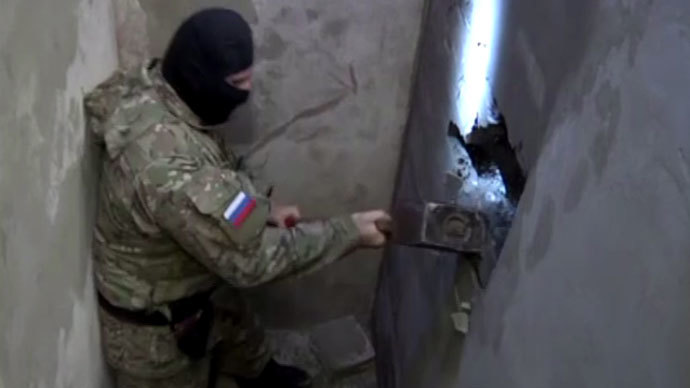 A police officer uses an ax to break the wall behind which a cache with amber is located. Screenshot from local police video, December 23, 2013, in Kaliningrad, Russia.