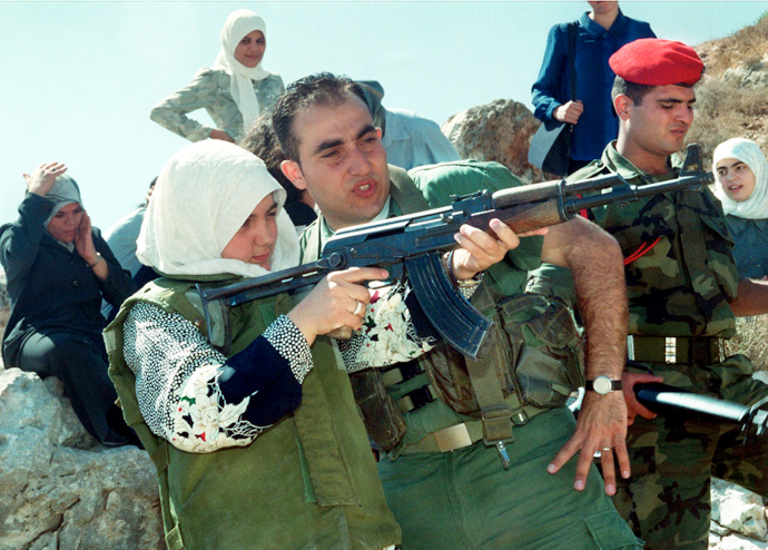A young Palestinian woman is trained in shooting an AK-47 automatic assault rifle as she wears a protective flak jacket during a graduation exercise in a military-style summer camp held August 10, 2000 outside Nablus in the northern West Bank. (Reuters)