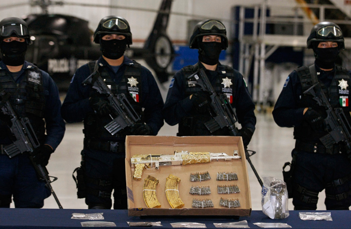 Federal policemen stand guard behind an AK-47 rifle and ammunition, confiscated during the arrest of suspect Ramiro Pozos Gonzalez alias "El Molca ", during a presentation to the media at the federal police headquarters in Mexico City September 12, 2012. (Reuters / Bernardo Montoya)