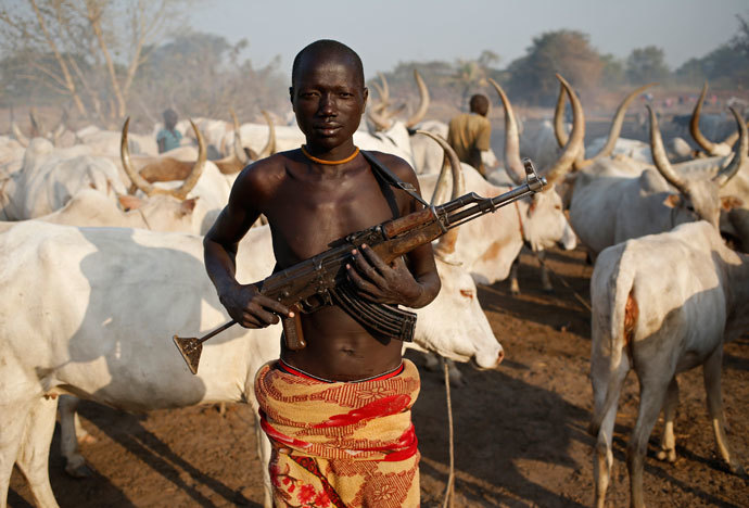 A man from Dinka tribe holds his AK 47 rifle in front of cows in a Dinka cattle herders camp near Rumbek, capital of the Lakes State in central South Sudan December 14, 2013.(Reuters / Goran Tomasevic)