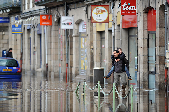 A man carries a boy in a flooded street in Morlaix, Britanny, where the city center is under 1.4 metres (four feet) of water on December 24, 2013. (AFP Photo / Frank Perry)