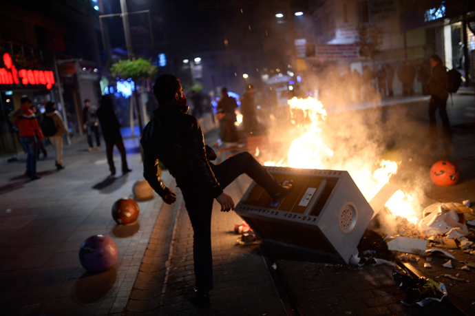 A man helps build a barricade as demonstrators clash with riot police (unseen) during a protest against corruption in the Kadikoy district of Istanbul on December 25, 2013 (AFP Photo / Bulent Kilic)