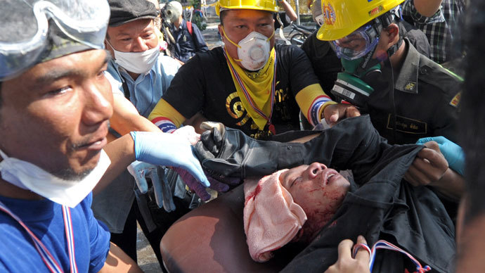 Thai anti government protesters carry an injured from gunshot during a rally at a stadium to register party-list candidates in Bangkok on December 26, 2013. (AFP Photo / Pornchai Kittiwongsakul)