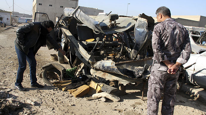 An Iraqi policeman looks at a damaged vehicle after a car bomb attack in Baghdad. December 16, 2013 (Reuters / Wissm al-Okili)