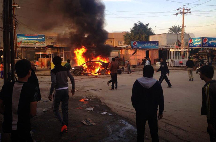 Iraqis gather around a burning car at the scene of an explosion in the Shiite Muslim Al-Amin district of Baghdad on December 8, 2013. (AFP Photo)