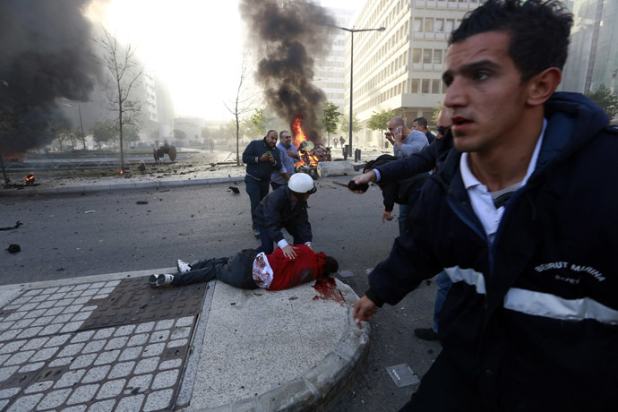 People run to help a wounded man as smoke rises from the site of an explosion in Beirut's downtown area December 27, 2013. (Reuters/Jamal Saidi)