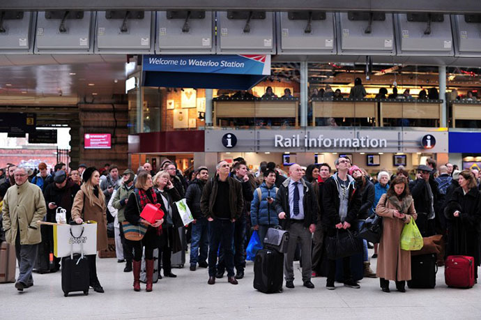People wait under departure boards at Waterloo train station in central London as disruption to rail services continues on December 24, 2013. (AFP Photo / Carl Court)