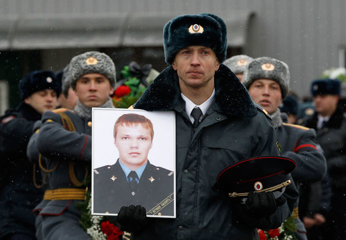 A police officer carries a portrait of Russian police senior sergeant Dmitry Makovkin who was killed by a suicide bomb blast in the city main railway station, in front of the funeral procession carrying Makovkin's coffin in Volgograd, January 2, 2014.(Reuters / Vasily Fedosenko)