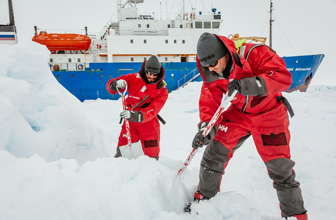 This image taken by expedition doctor Andrew Peacock of www.footloosefotography.com on December 31, 2013 shows scientists from the University of New South Wales in Australia, Ziggy Marzinellia and Graeme Clark, preparing a suitable surface for a helicopter landing next to the MV Akademik Shokalskiy (background), still stuck in the ice off East Antarctica. (AFP Photo)