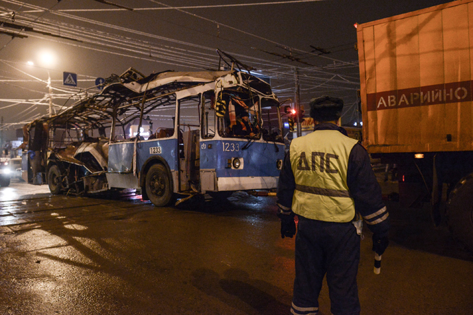 A policeman watches as a bus, destroyed in an earlier explosion, is towed away in Volgograd December 30, 2013 (Reuters / Sergey Karpov)