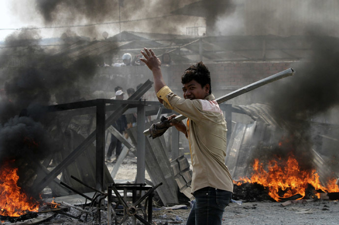 A worker carrying a metal rod reacts after clashes broke out during a protest in Phnom Penh January 3, 2014. (Reuters/Samrang Pring)