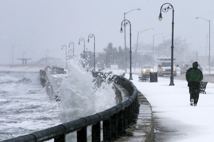 A man jogs past waves crashing against the seawall around high tide during a winter nor'easter snowstorm in Lynn, Massachusetts January 2, 2014. (Reuters/Brian Snyder)