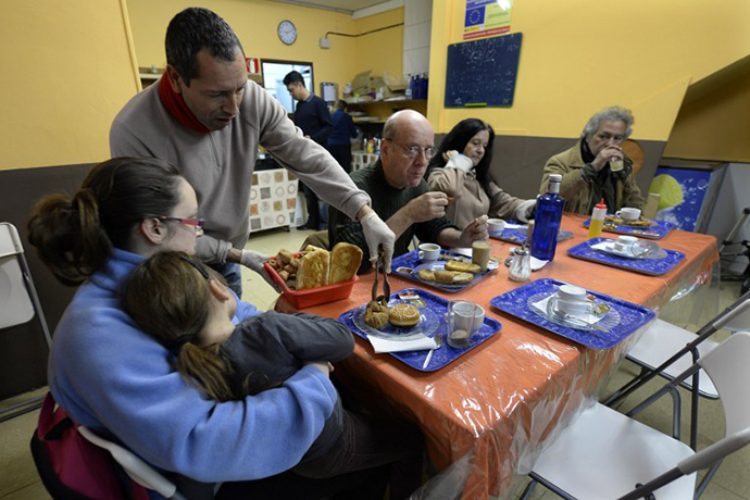 People have breakfasts at a soup kitchen in Barcelona on December 17, 2013. For the past three years, the soup kitchen has been serving up hot breakfasts to the needy. Unlike most of Spain's economy, it is experiencing high demand. (AFP Photo / Llius Gene)