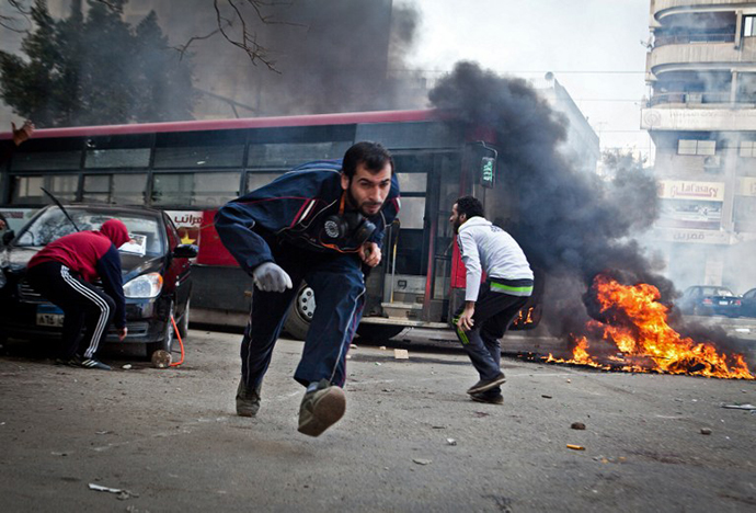 Supporters of Egypt's deposed president Mohamed Morsi run for cover from tear gas fired by riot police during clashes in the northeastern part of Cairo's Nasr City district on January 3, 2014. (AFP Photo / Virginie Nguyen Hoang)