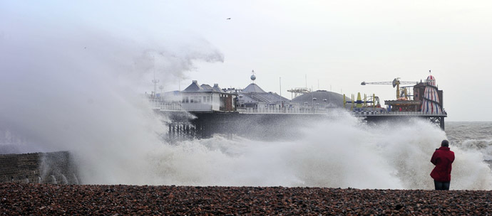 A man photographs Brighton Pier in southern England in southern England on January 3, 2014 as waves strike after a high tide. (AFP Photo/Carl Court)