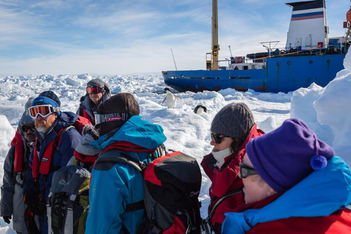 The first load of passengers from the stranded Russian ship MV Akademik Shokalskiy (back R) wait for a helicopter from the nearby Chinese icebreaker Xue Long to pick them up as rescue operations take place after over a week of being trapped in the ice off Antarctica. (AFP Photo / Andrew Peacock )