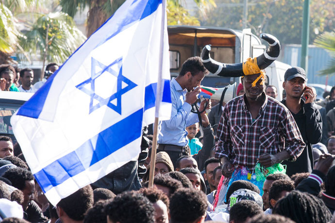 Protestors wave an Israeli flag as thousands of African asylum seekers demonstrate outside several Western embassies in the Mediterranean coastal city of Tel Aviv on January 6, 2014.(AFP Photo / Jack Guez)
