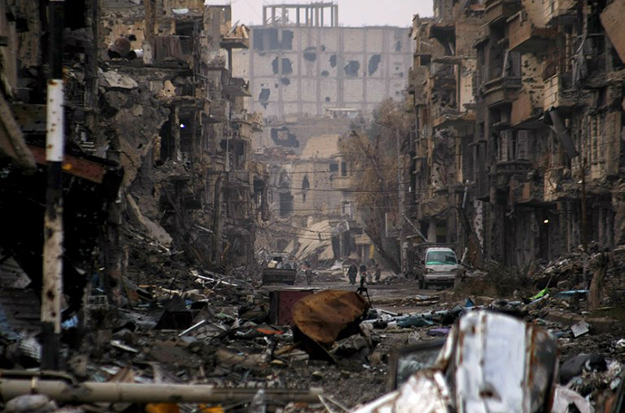 Syrians walk along a severely damaged road in the northeastern city of Deir Ezzor on January 4, 2014. (AFP Photo / Ahmad Aboud)